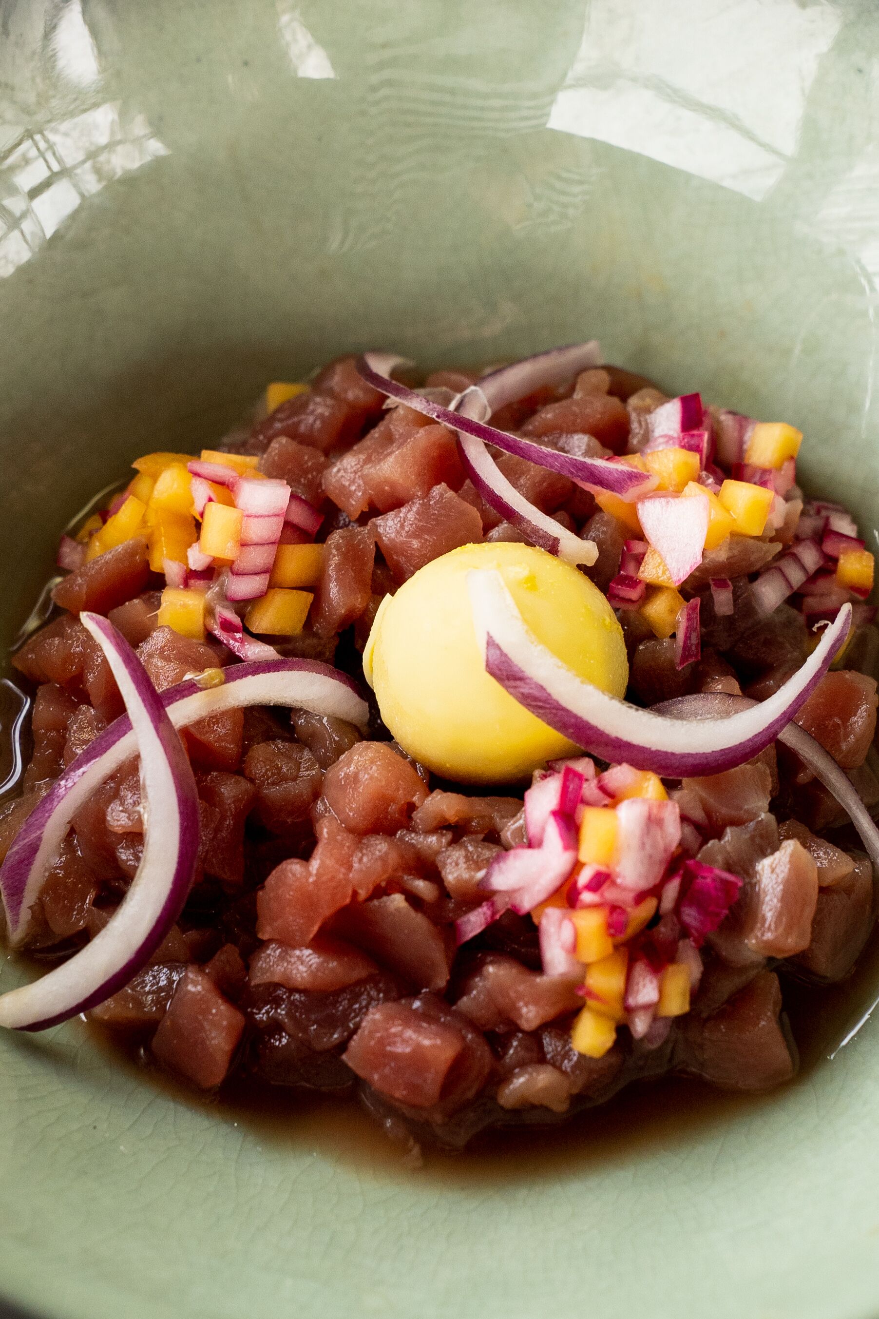 Un bol de ceviche garni d’oignons rouges coupés en dés, de mangue et d’un œuf dur.
