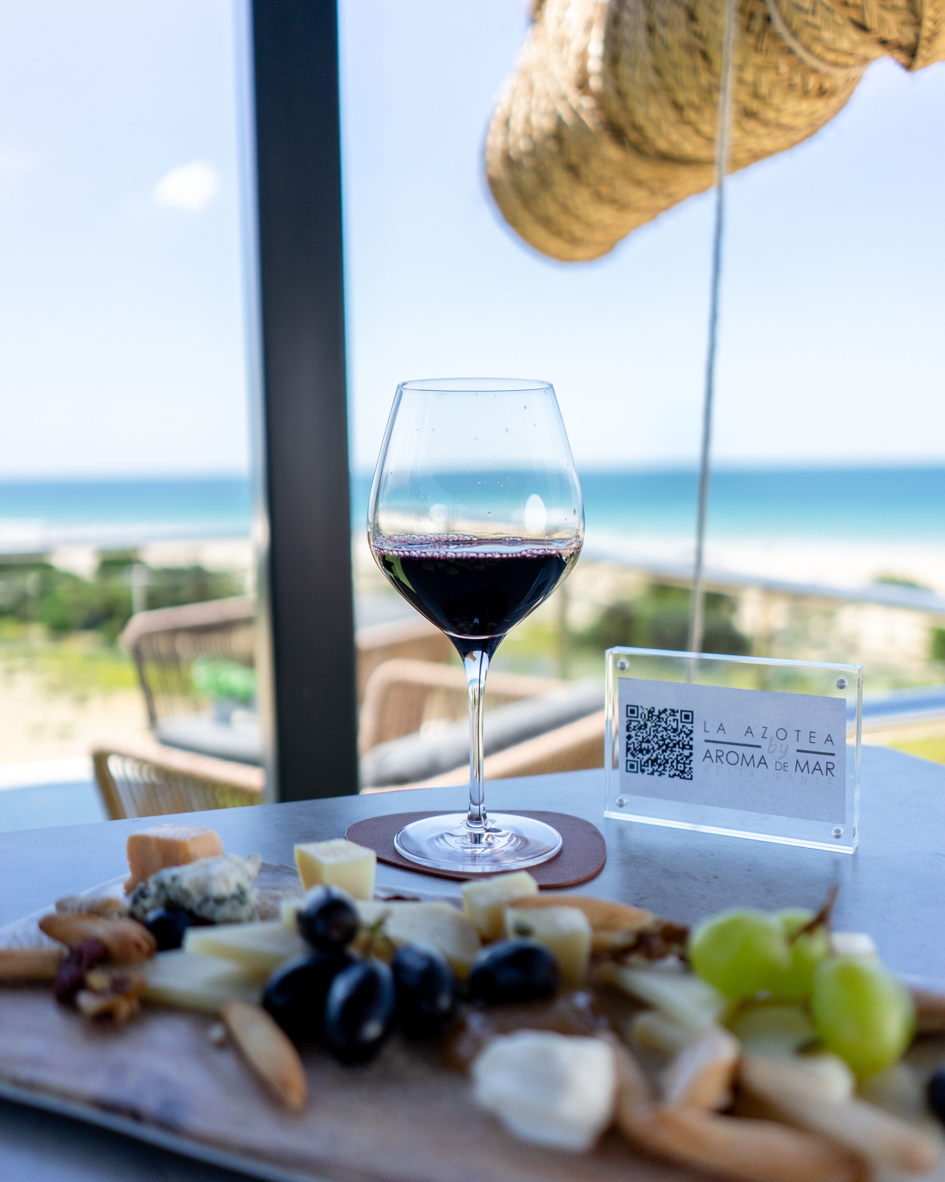 A table with a wine glass, cheese platter, and a QR code sign.