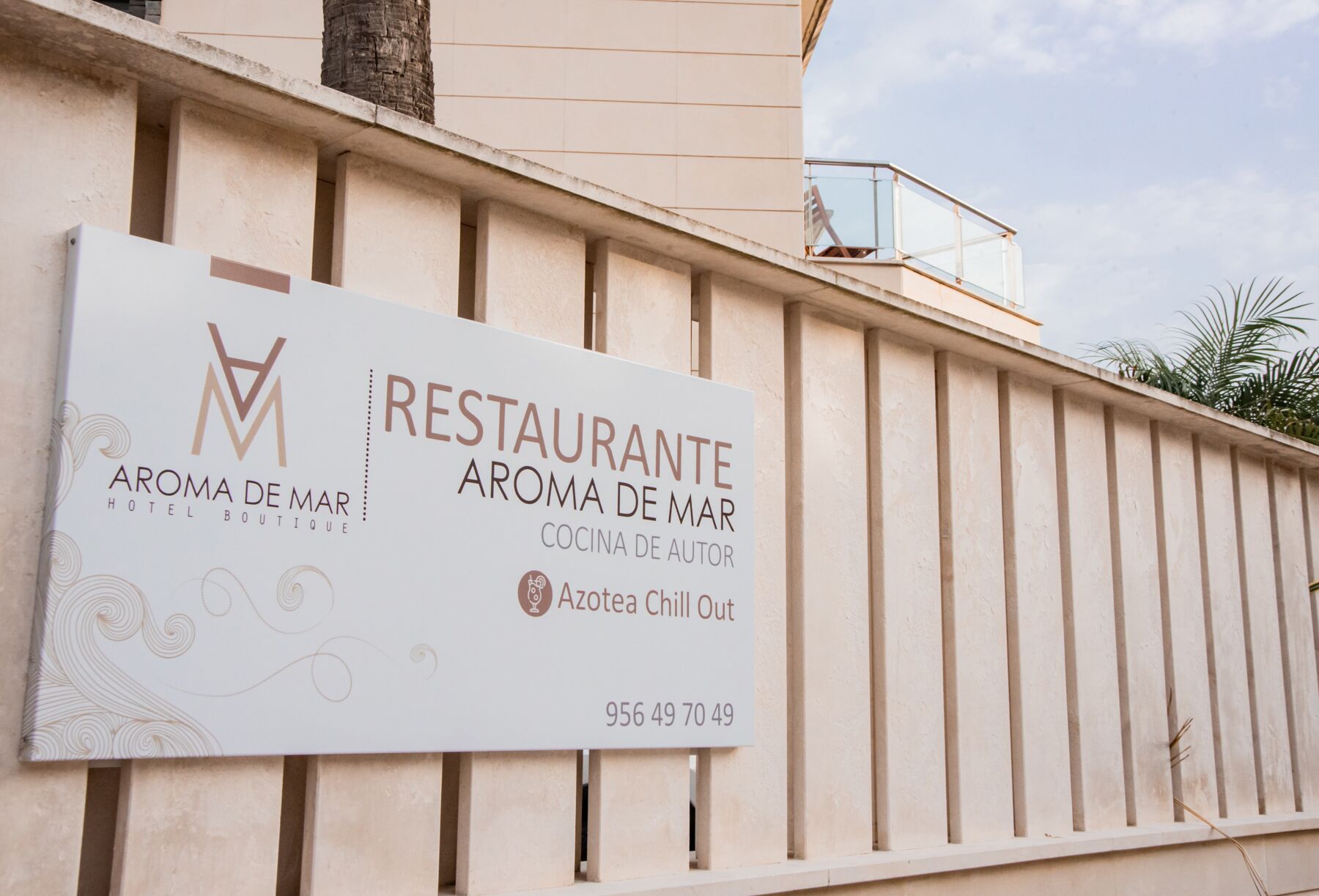 A sign for 'RESTAURANTE AROMA DE MAR HOTEL BOUTIQUE' with a contact number.