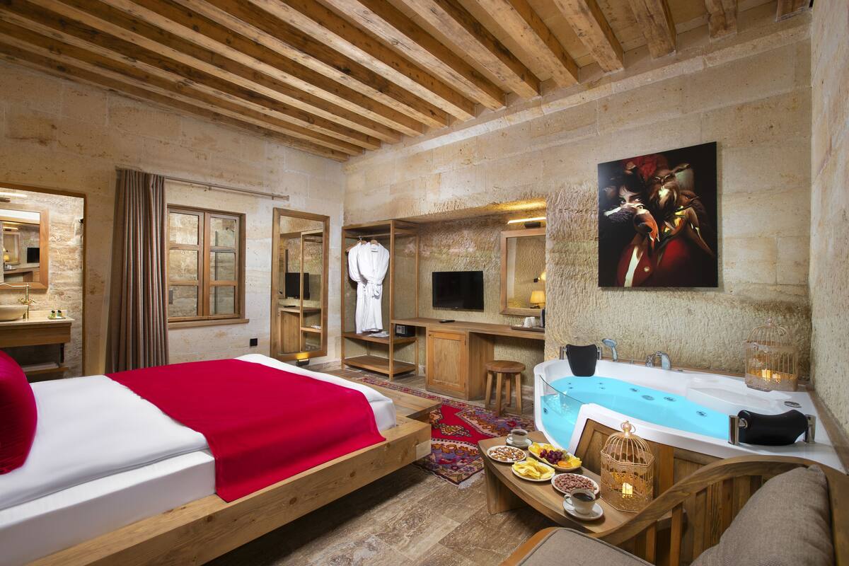 A cozy room with a bed, a wooden desk, a bathtub, and a dining area with a table set for a meal.