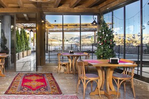 Enjoy a serene dining experience with a view of the surrounding mountains from this cozy space, featuring a festive tree and comfortable seating.