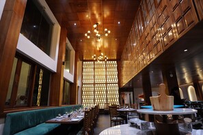 A restaurant with wooden paneling, a high ceiling, and a central light fixture. Tables are set with cutlery and glasses. - ORSINO RESORT MALL ROAD (Darjeeling)