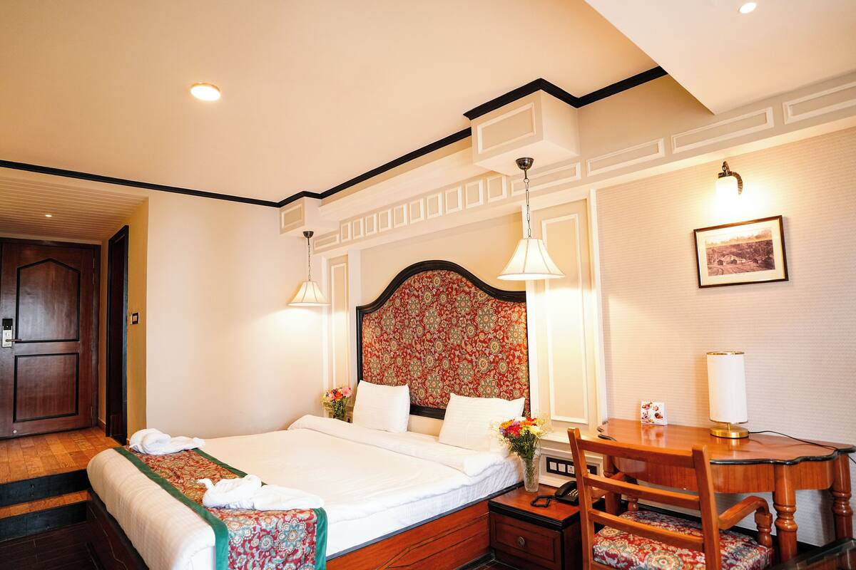 A hotel room with a large bed, a wooden desk, and a chair.