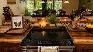 Una cocina con estufa de acero inoxidable, armarios de madera, una placa vitrocerámica y vistas al exterior.