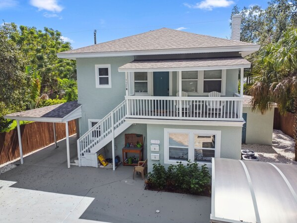 Ein zweistöckiges Haus mit Balkon, überdachter Terrasse und kleinem Garten.