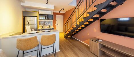Eine moderne Küche mit Bar, einer Treppe und einem Fernseher an der Wand.