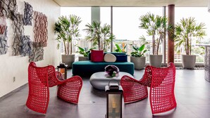 A modern living room with a sofa, red chairs, and potted plants. - Charlie For You Moema (São Paulo)