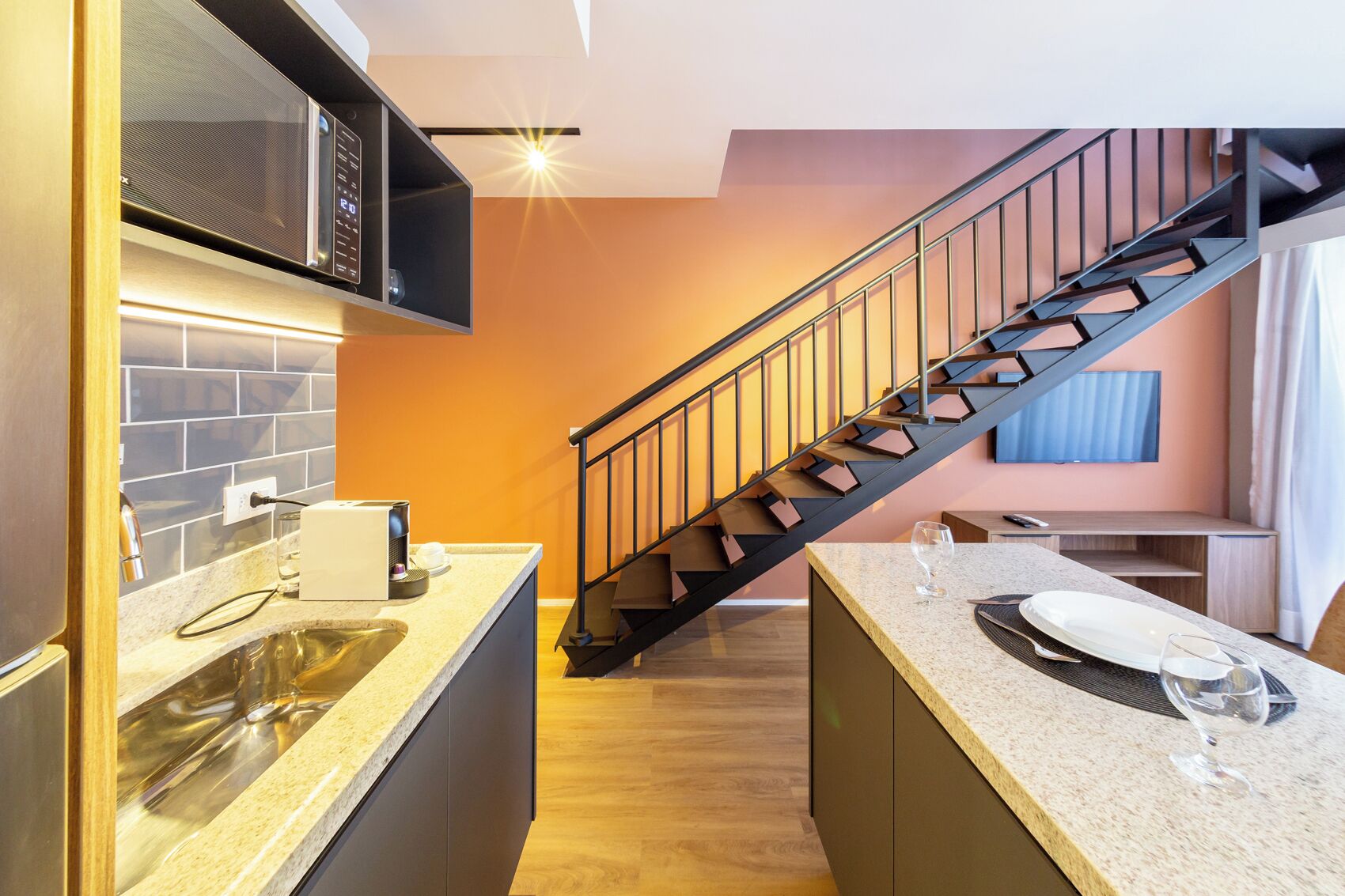 A modern kitchen with a built-in microwave, a sink, and a countertop with a toaster and glassware.