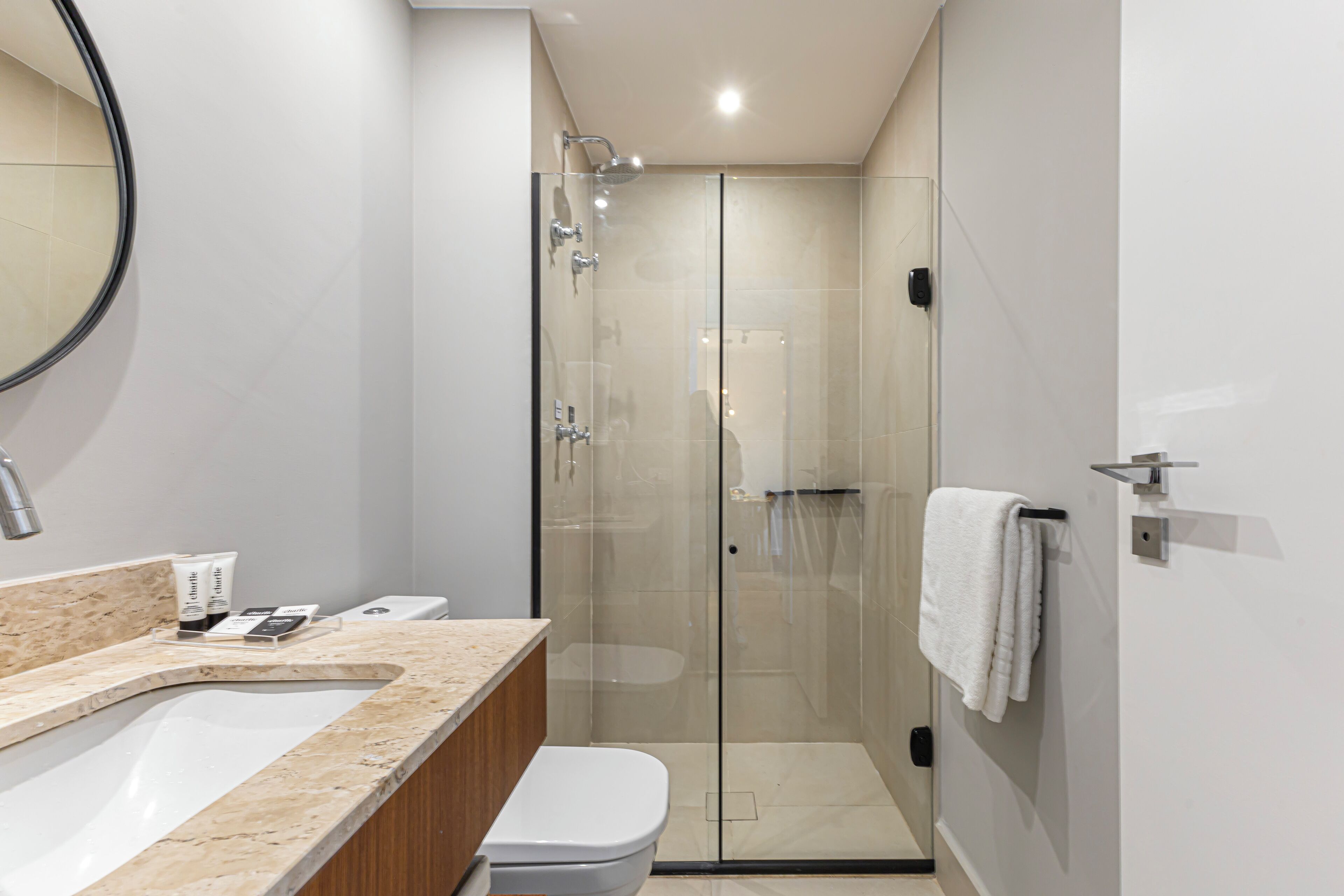 A modern bathroom with a glass-enclosed shower, a sink with a marble countertop, and a toilet.