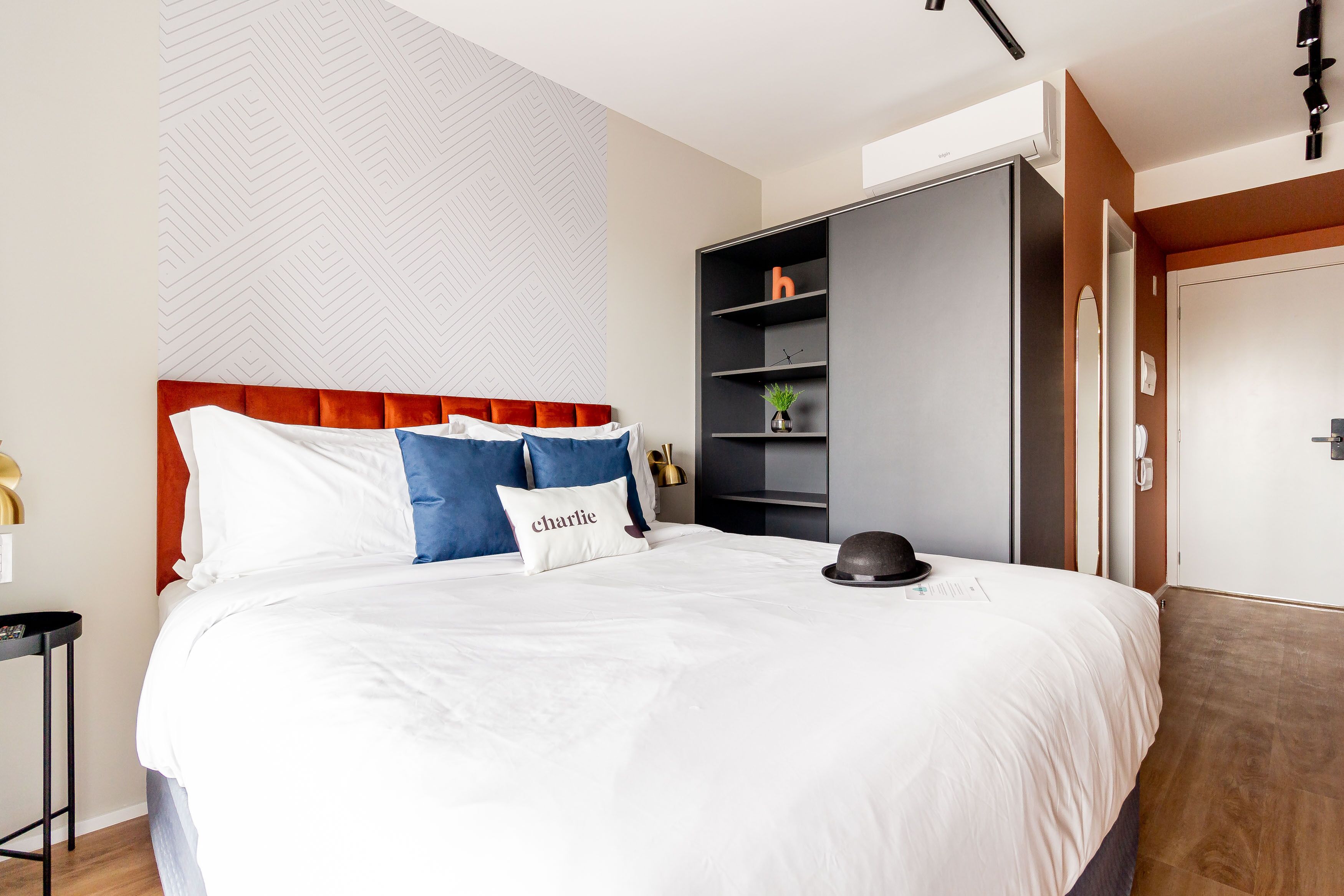A modern hotel room with a large bed, a wardrobe, and a small table.