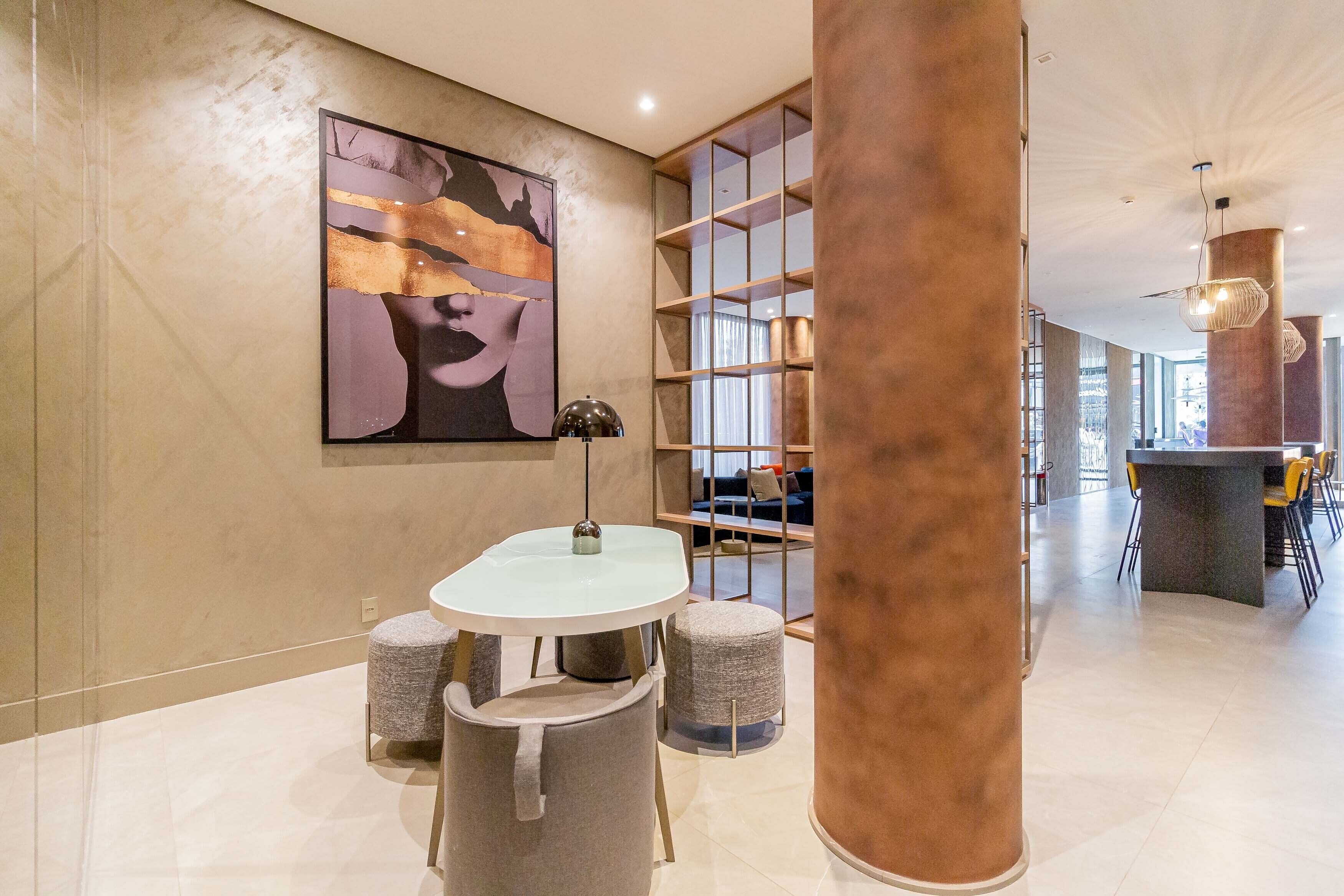 Un interior moderno con una zona de comedor minimalista, un cuadro abstracto grande y una zona de bar/lounge con vistas.