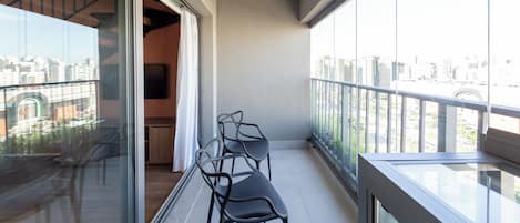 A balcony with a city view, a sliding door, and two chairs.