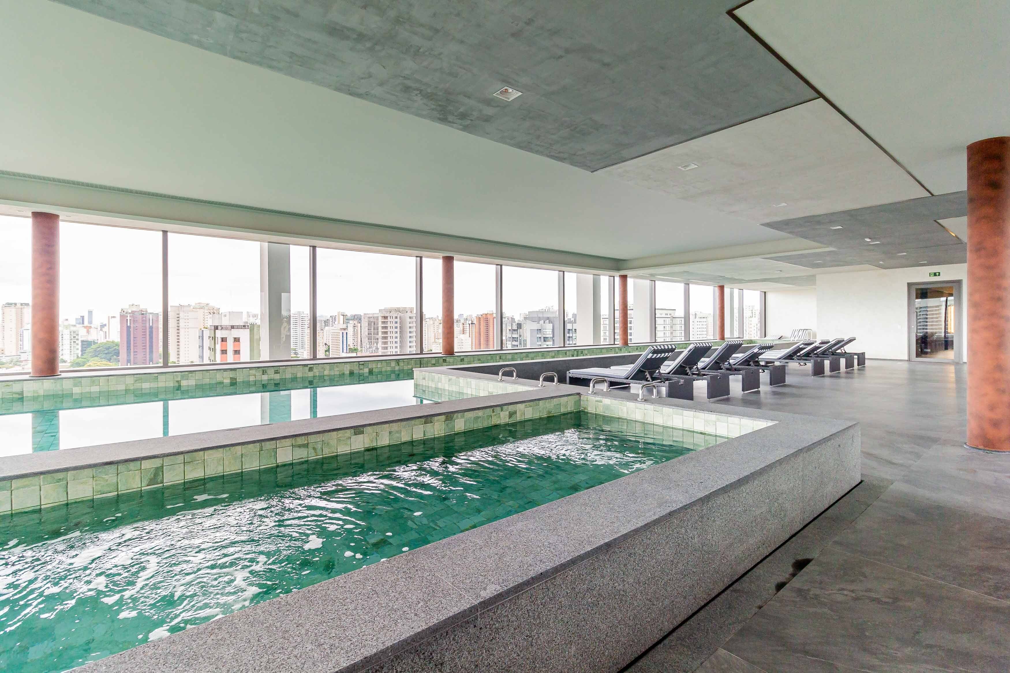 Una piscina en la azotea con vistas despejadas del horizonte de la ciudad, ventanas amplias y sillones de descanso.