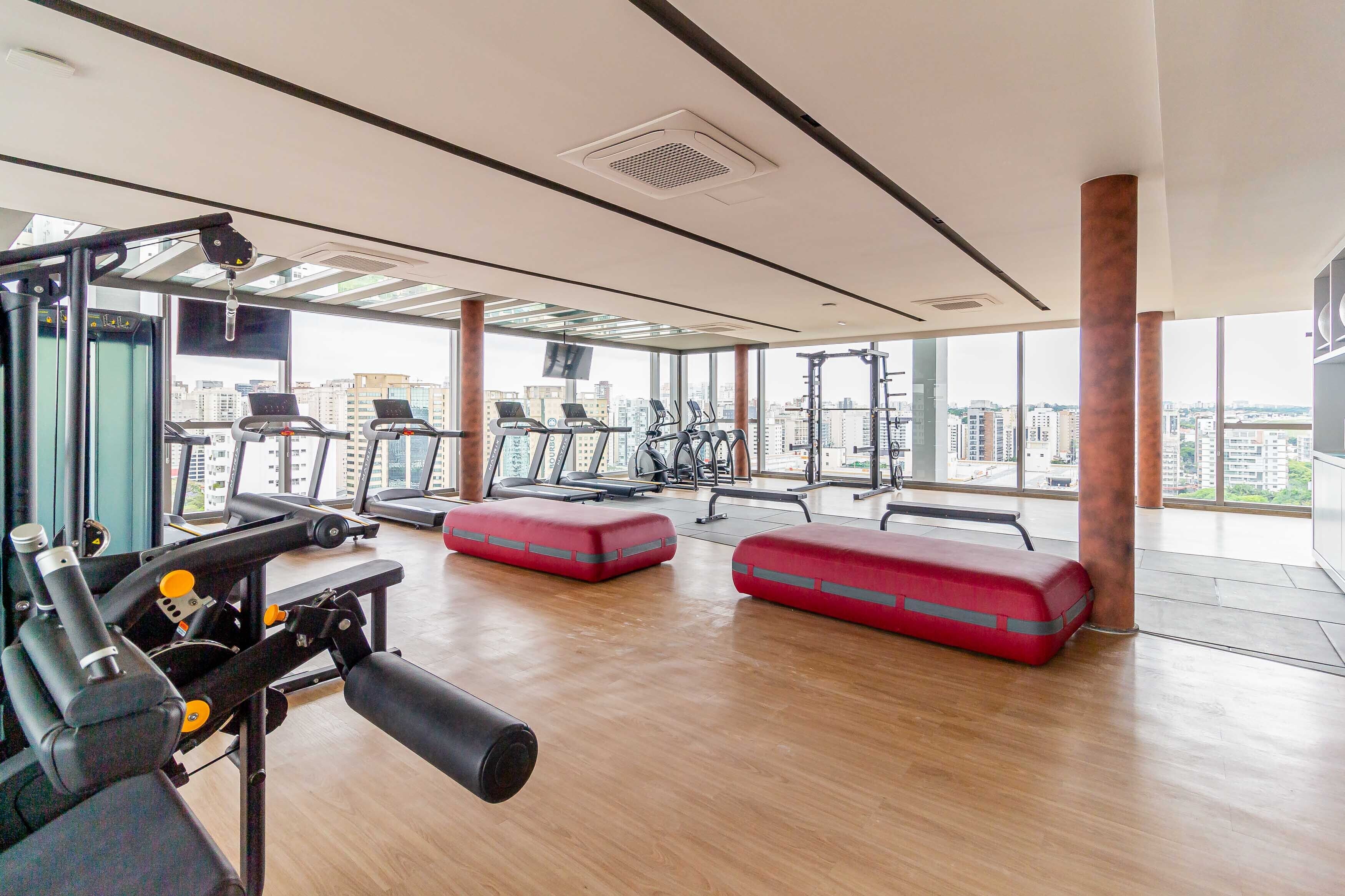 Un'ampia palestra con macchinari cardio, panche per pesi e pod per esercizi rossi.