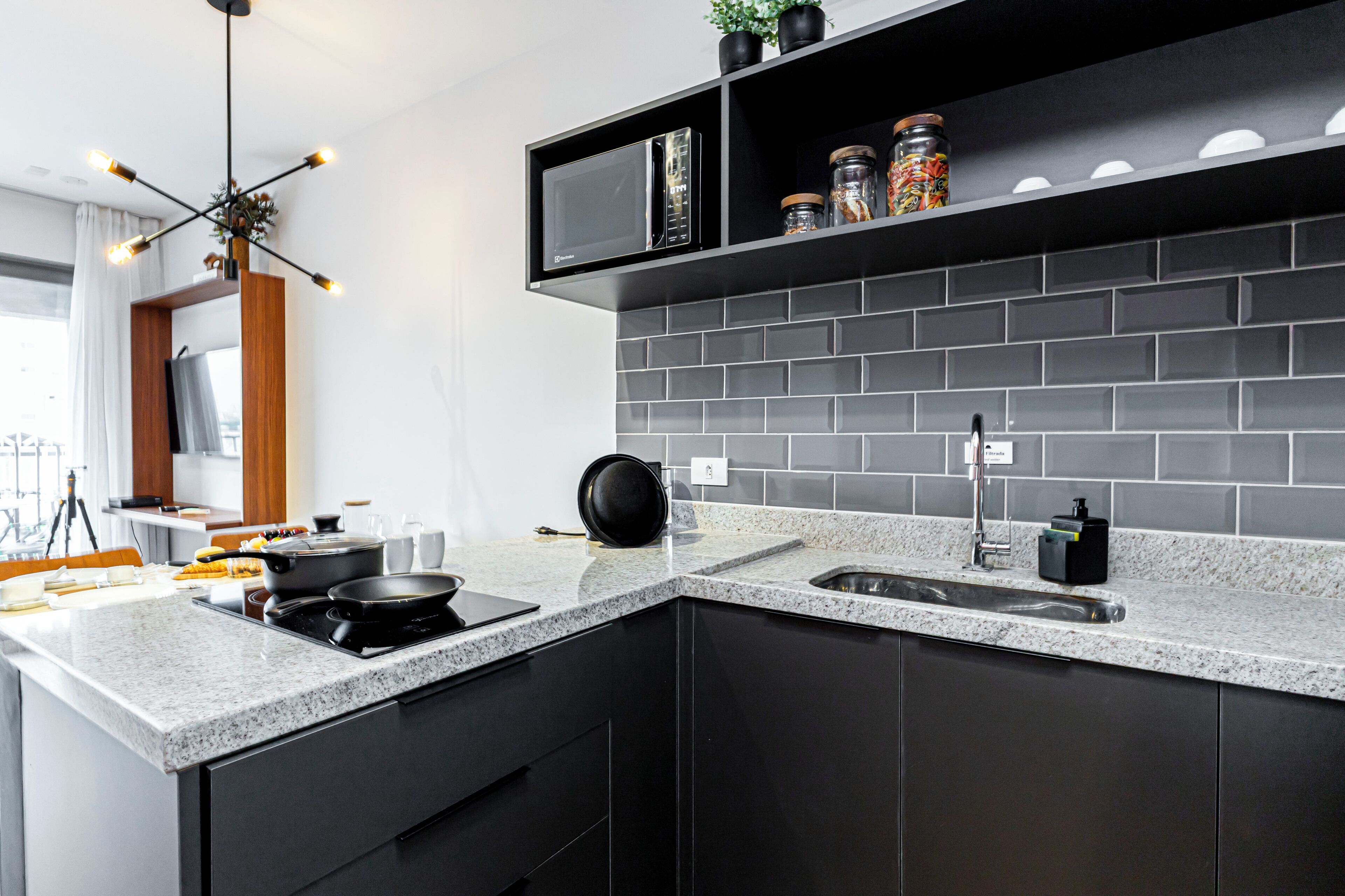A modern kitchen with a granite countertop, black cabinets, a built-in microwave, and a black pot on the stove.