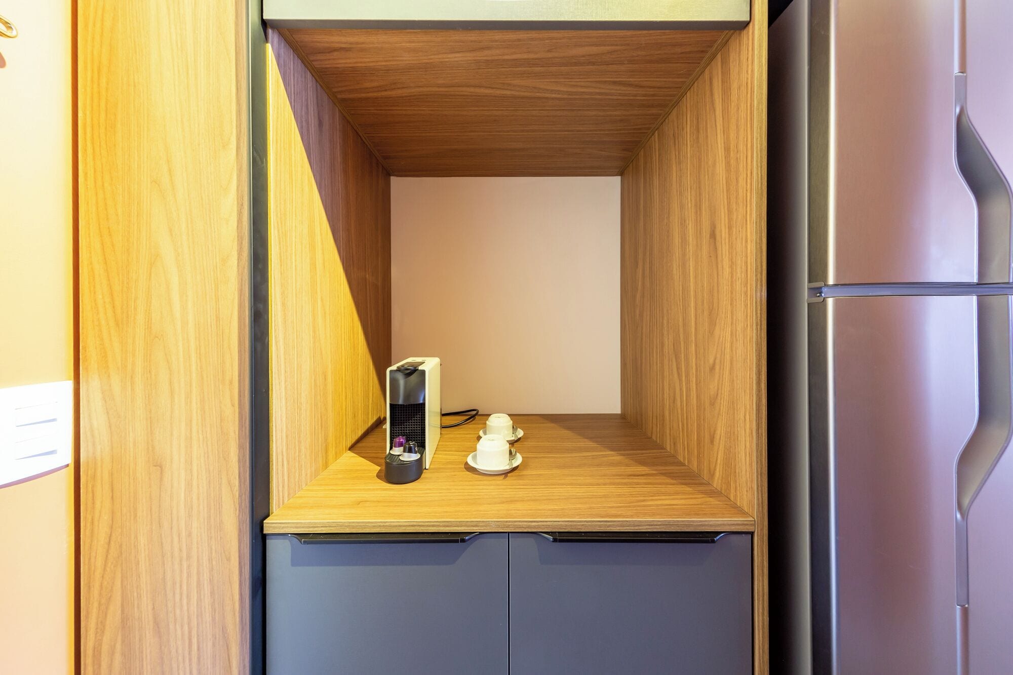 A compact kitchenette with a wooden countertop, a coffee machine, and a small refrigerator.