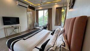 A modern hotel room with a large bed, a flat-screen TV, a small side table, and a chair.