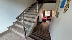A staircase with metal railings leading to a landing where a red sofa and a small table are placed.
