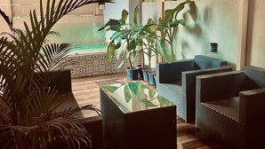 A cozy indoor seating area with wicker furniture, a wooden ceiling, and potted plants. - Clarence Cottage Villa 27 (Marra)