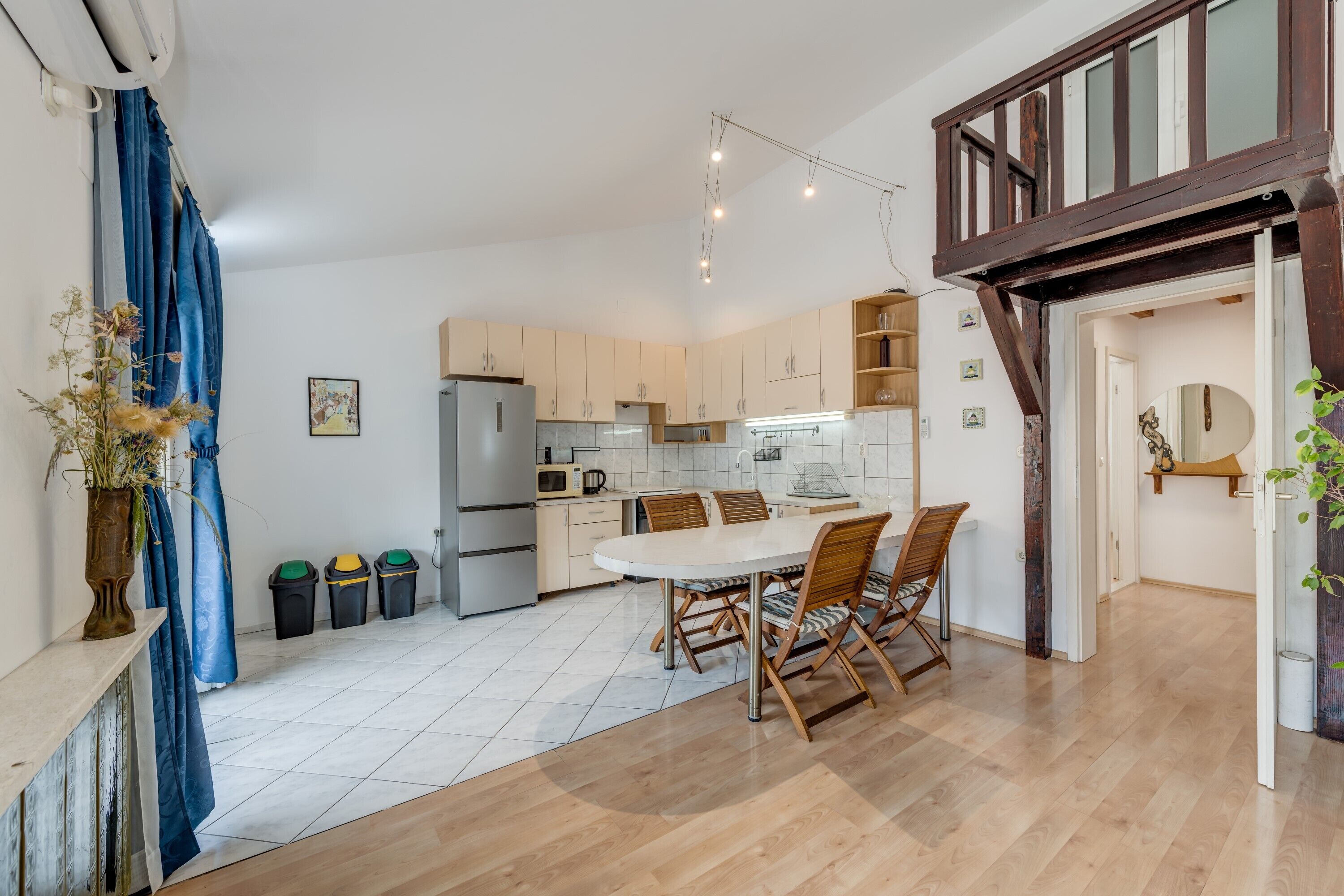 Una cocina moderna con armarios blancos, una mesa de comedor con sillas y una escalera de madera.
