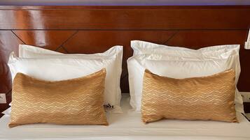 A bed with white pillows and two decorative pillows with a gold pattern.