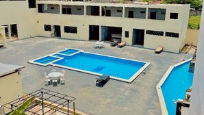 Piscina en la azotea con sillas de descanso y zona de estar techada.