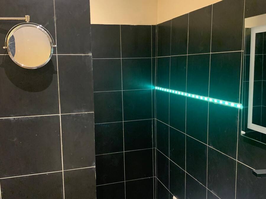 Un bagno con piastrelle nere, un lavandino bianco e uno specchio.