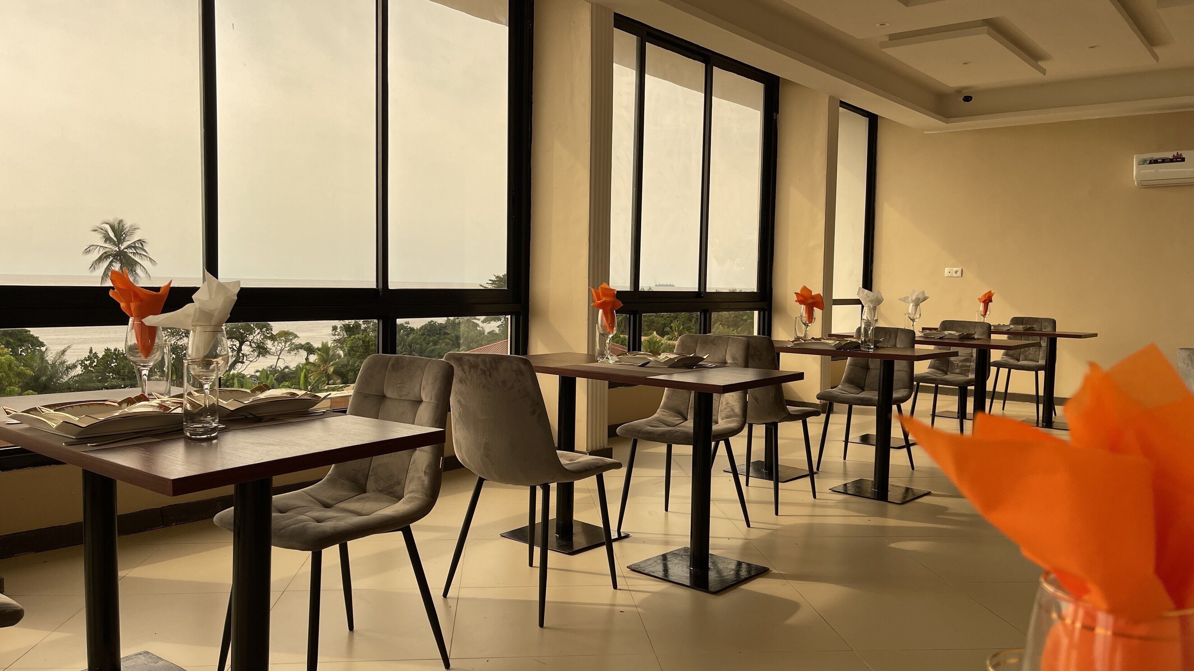 Un comedor con mesas y sillas, ventanas amplias y vistas al exterior.