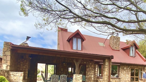 Un edificio de piedra con techo rojo, un porche cubierto y una chimenea de piedra.