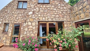 Una casa de piedra con techo triangular, dos ventanas y una puerta de madera.