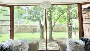 Una habitación con un ventanal grande, un aplique de techo y un banco cubierto de piel con cojines.