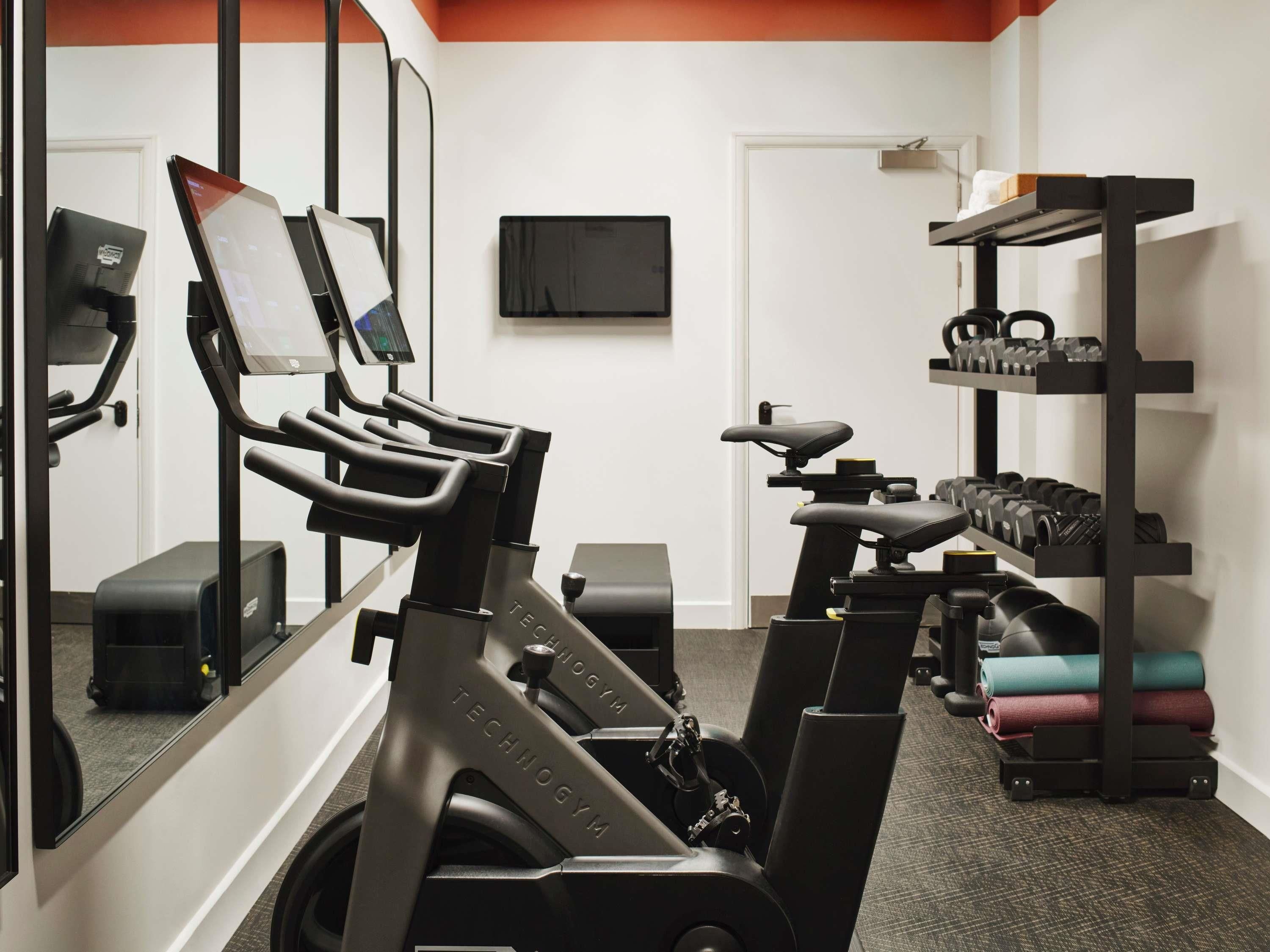 A gym with stationary bikes, a treadmill, and a rack of dumbbells.