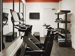 A gym with stationary bikes, a treadmill, and a rack of dumbbells. - Hyde London City - St Paul’s (London)