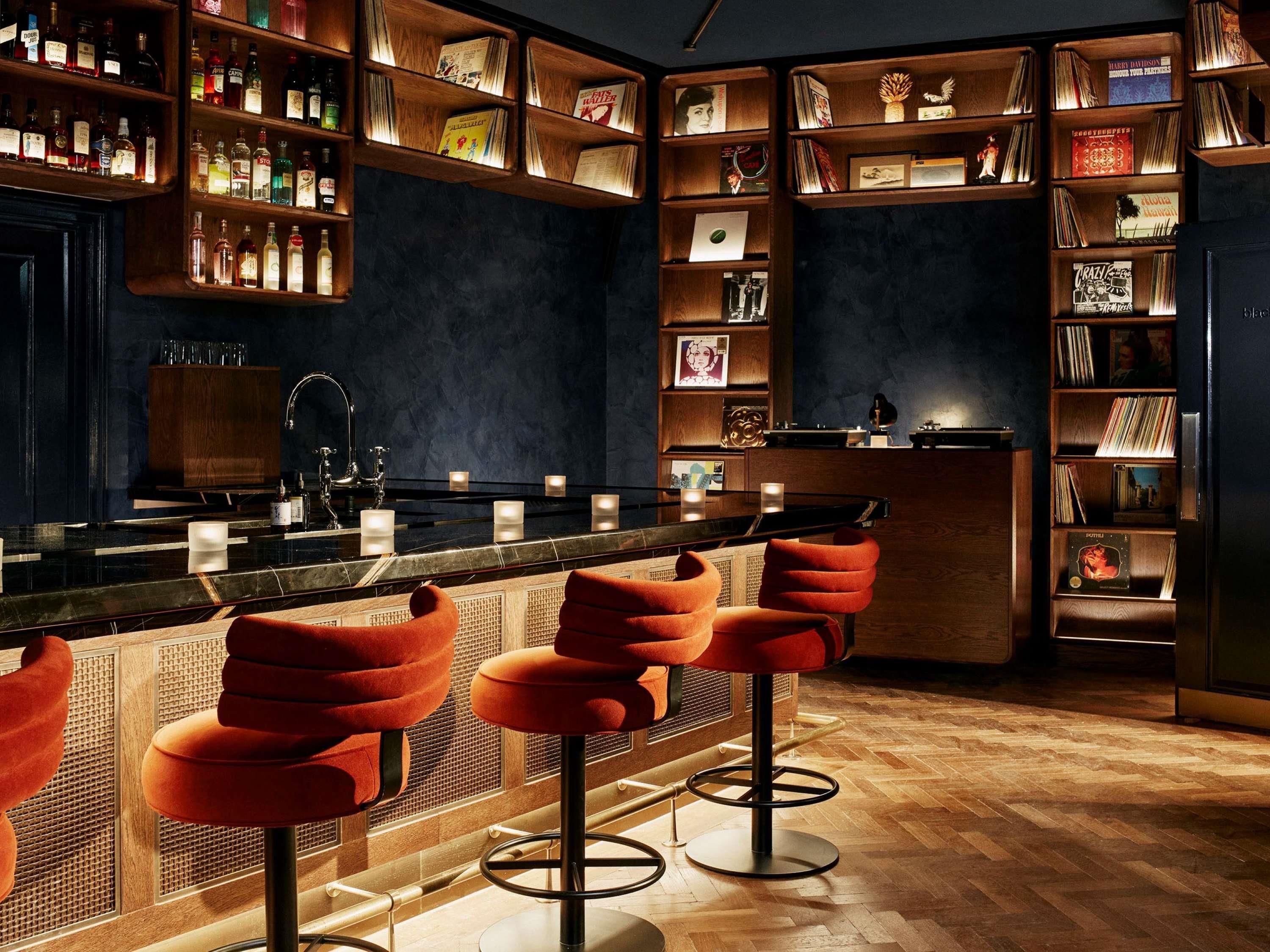 A bar area with wooden shelves, bar stools, and a counter.
