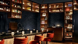A bar area with wooden shelves, bar stools, and a counter. - Hyde London City - St Paul’s (London)