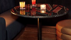 A corner seating area with a round table, two drinks, and a candle. - Hyde London City - St Paul’s (London)