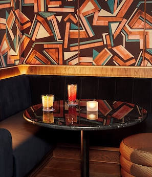 A corner seating area with a round table, two drinks, and a candle. - Hyde London City - St Paul’s (London)