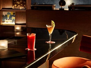 A bar area with two drinks on a reflective surface, a candle, and a chair. - Hyde London City - St Paul’s (London)