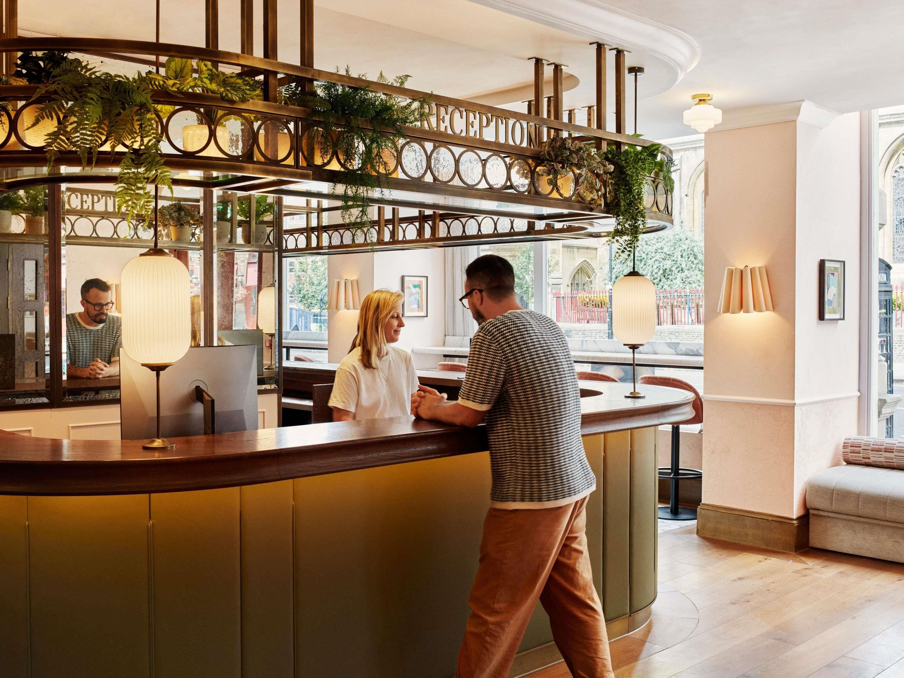 A reception desk with a modern design, featuring a curved wooden counter and decorative metal railings.