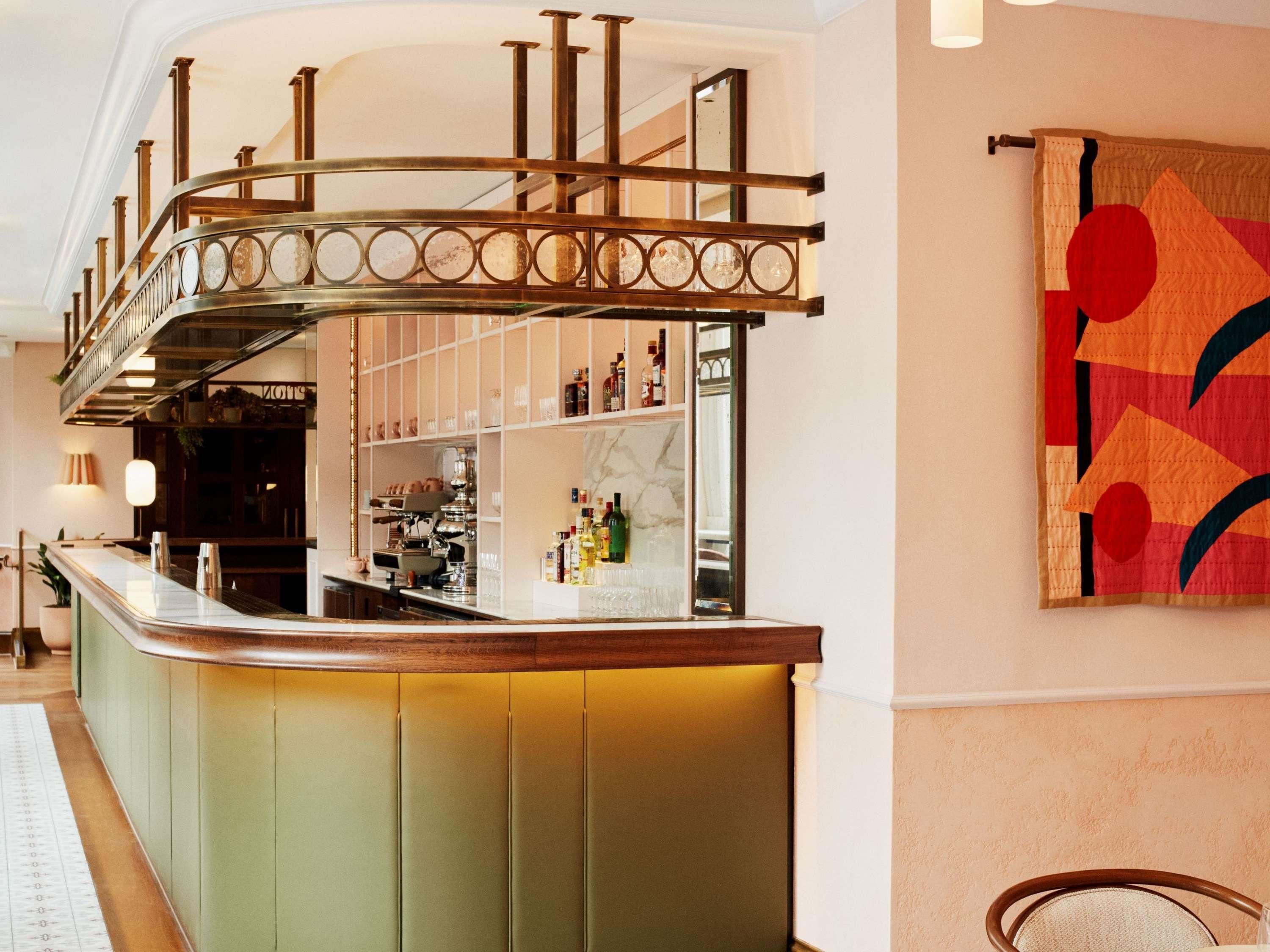 A bar area with a curved counter, shelves with bottles, and a decorative wall piece.