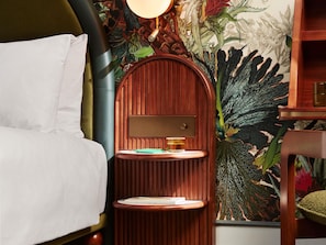 A bed with white linens, a wooden nightstand with a lamp, and a wall with a floral wallpaper. - Hyde London City - St Paul’s (London)