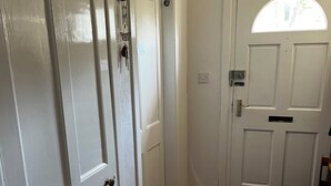 A hallway with white doors, a wooden floor, and a small window.
