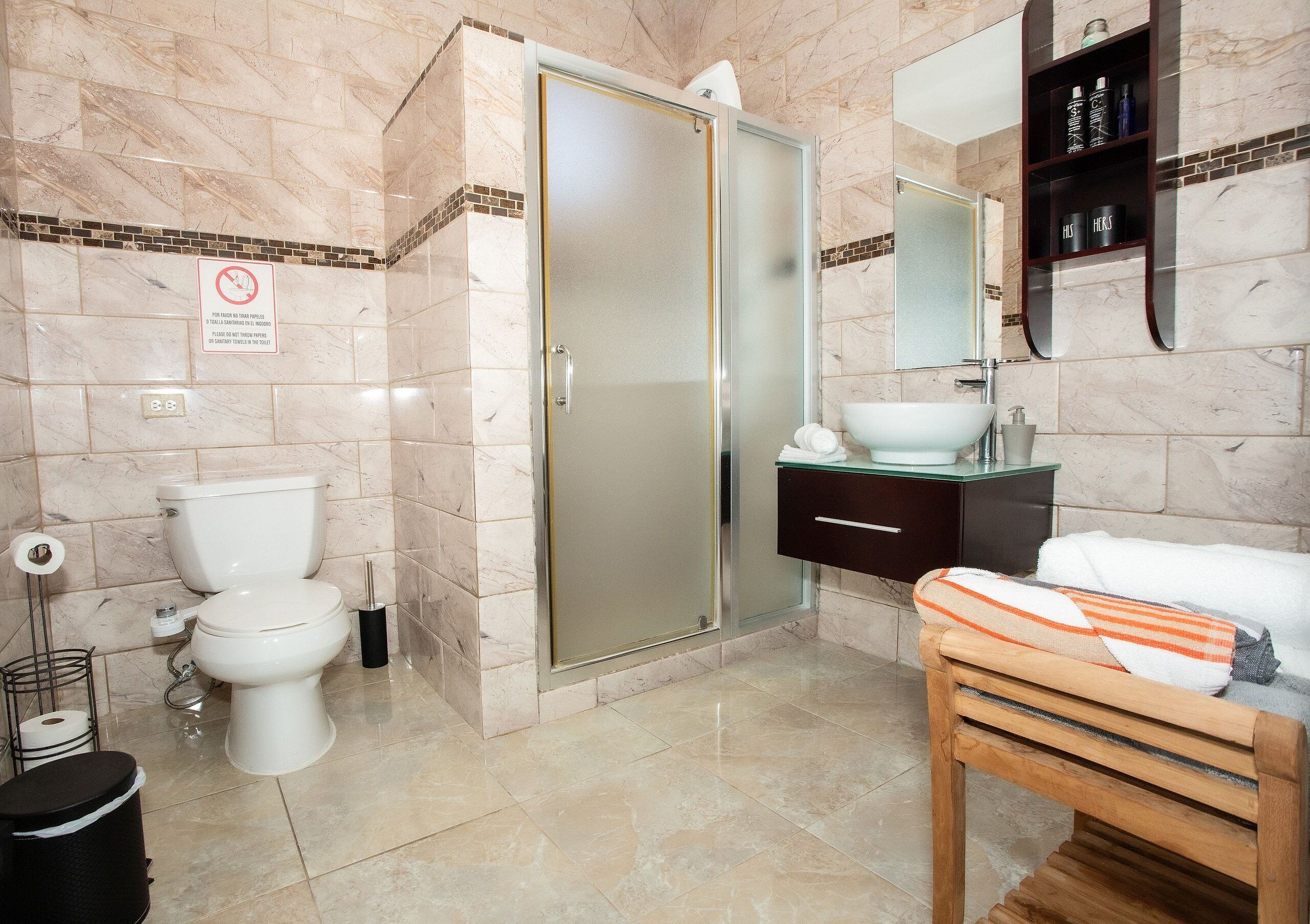 A bathroom with a toilet, shower, sink, and a towel rack.
