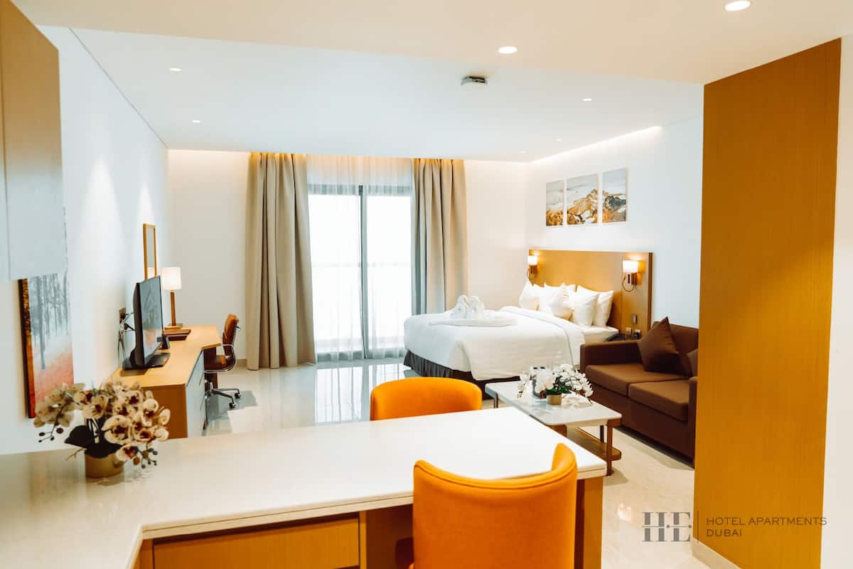 A hotel room with a bed, a desk with a chair, a sofa, and a TV.