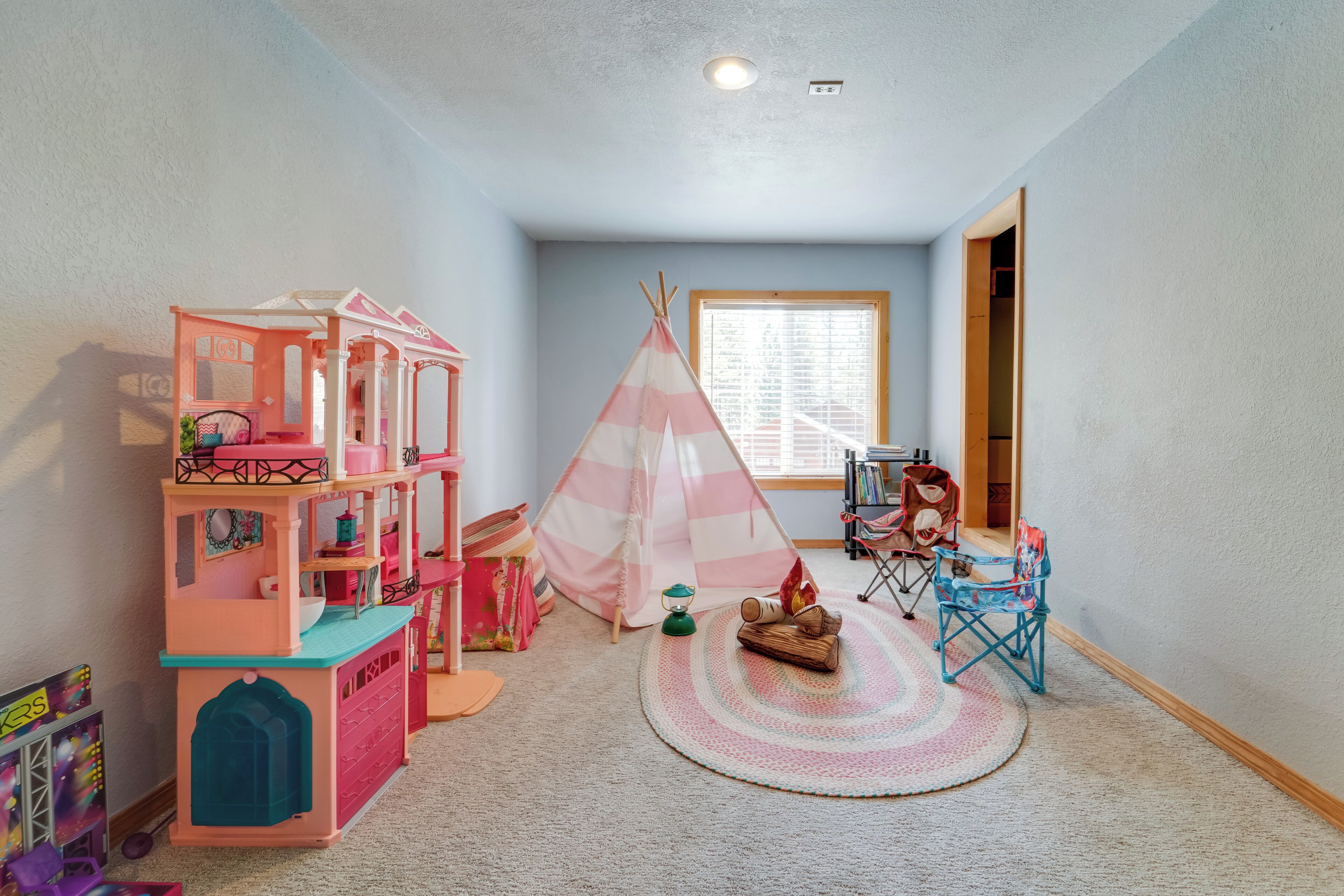 A child's playroom with a playhouse, a teepee, and a small round rug.