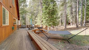 A wooden deck with outdoor furniture, including a table and chairs, surrounded by tall trees. - 4 Mi to Downhill Ski Resort! Spacious Family Haven (Truckee)