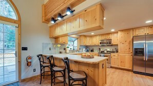 A modern kitchen with wooden cabinets, a stainless steel refrigerator, and a large island with bar stools. - 4 Mi to Downhill Ski Resort! Spacious Family Haven (Truckee)