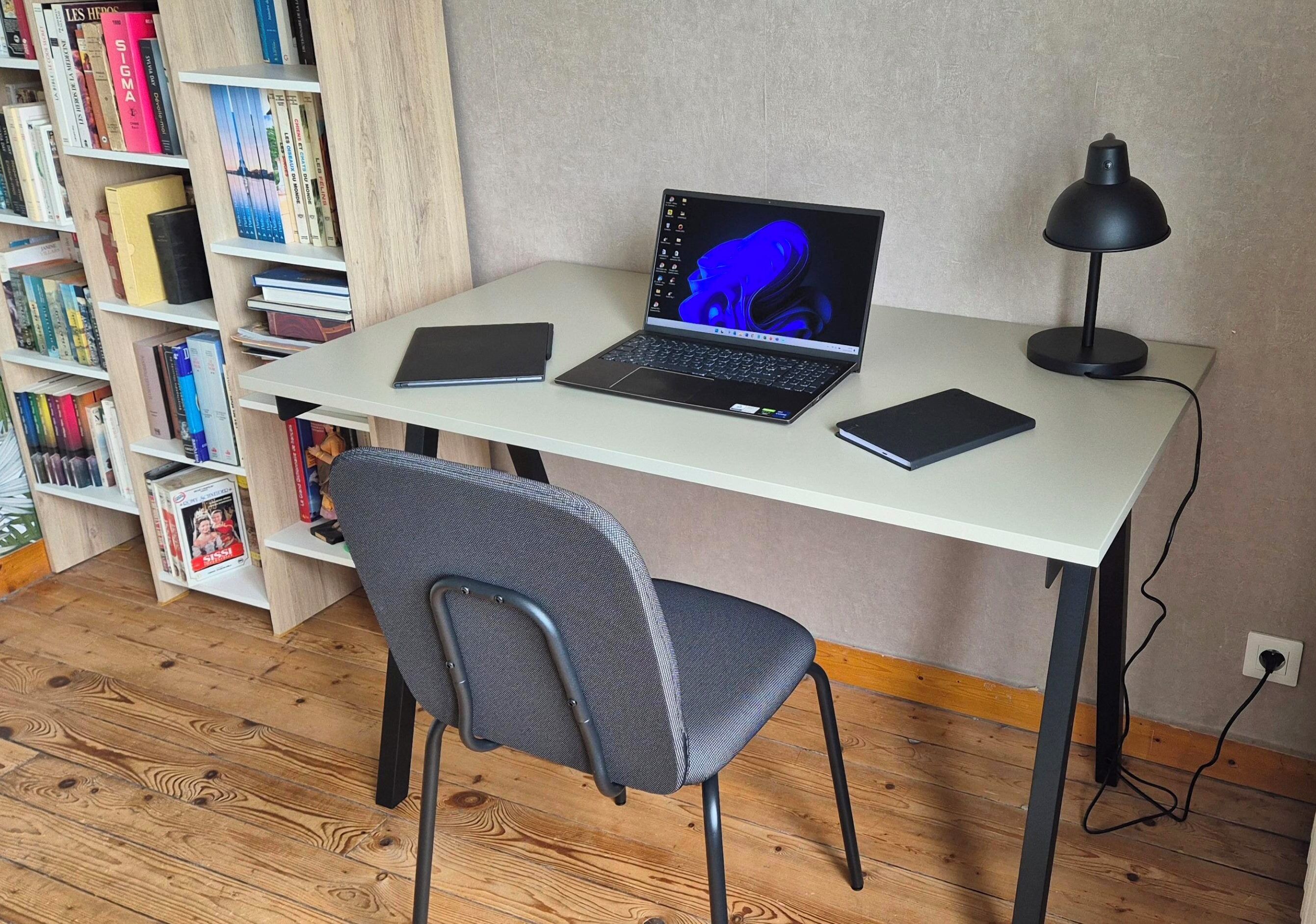 Ein Arbeitsplatz mit einem Laptop, zwei Tablets, einer Schreibtischlampe und einem Stuhl.