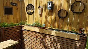 Een houten terras met ingebouwde plantenbakken, een vogelhuisje en een vogelvoeder.