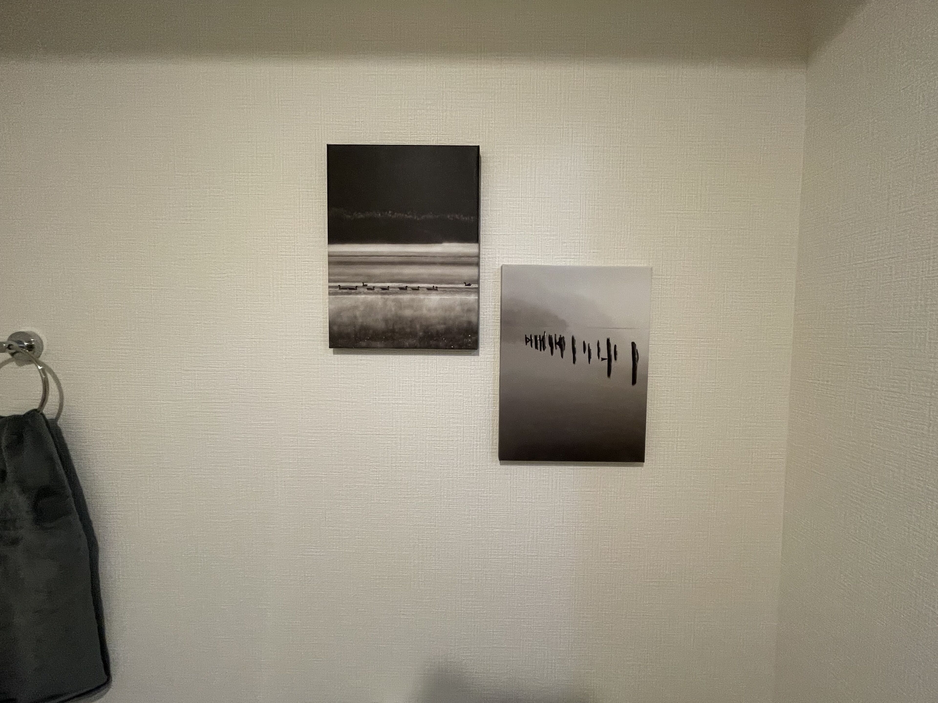 Eine Wand mit zwei gerahmten Fotografien und einem Handtuchhalter.
